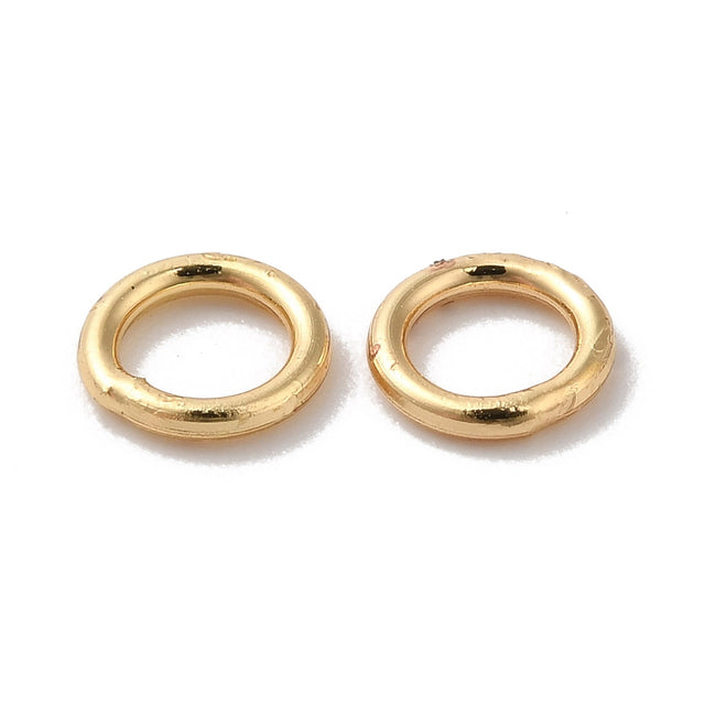 Pair of gold closed soldered jump rings on a white background