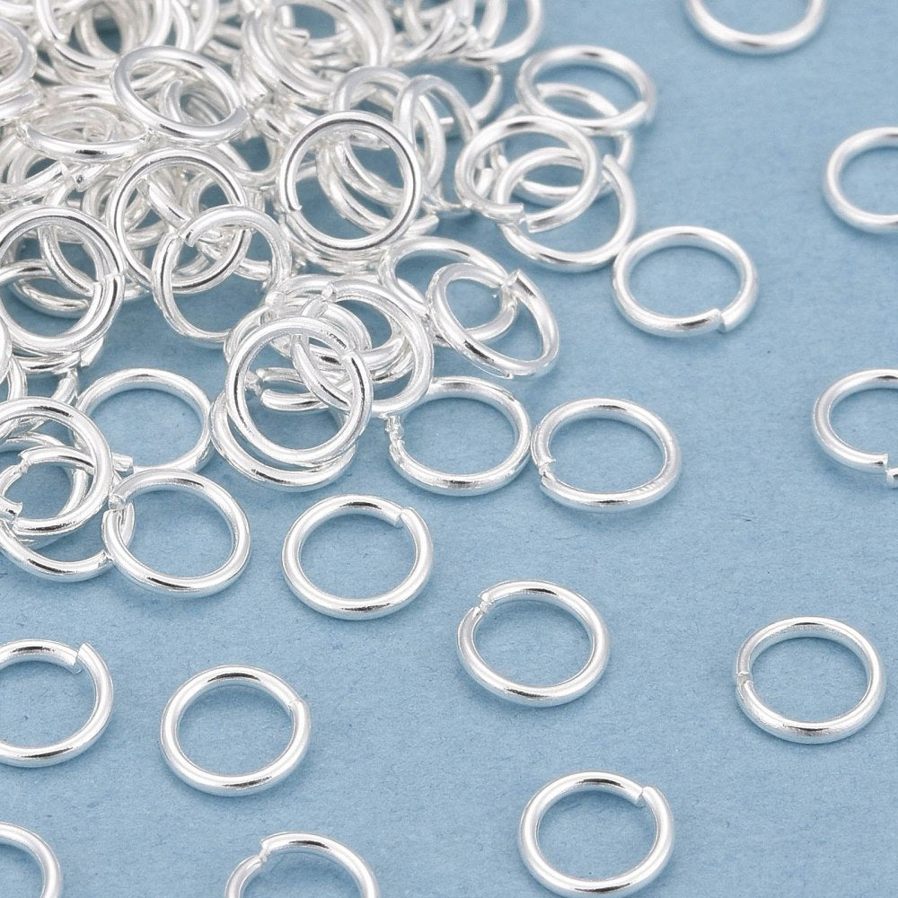Silver jump rings scattered on a blue background