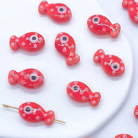 Red fish-shaped bead art decorations with white polka dots on a white background.