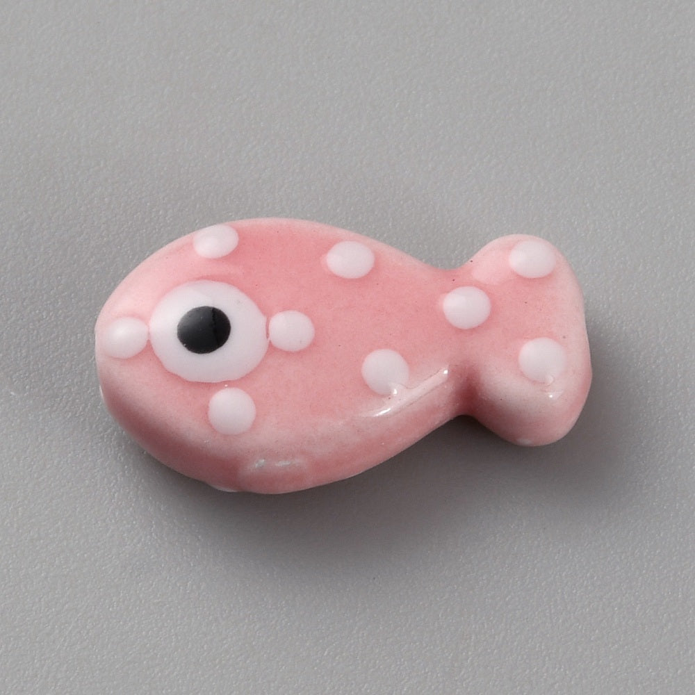 Pink fish-shaped bead with white spots and a black eye on a gray background