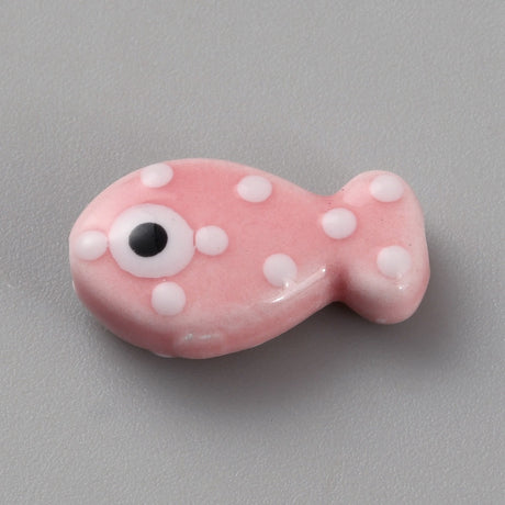 Pink fish-shaped bead with white spots and a black eye on a gray background