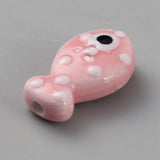 Pink fish-shaped bead with white spots and a black eye on a gray background