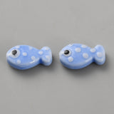 Two blue fish-shaped beads with white polka dots on a gray background