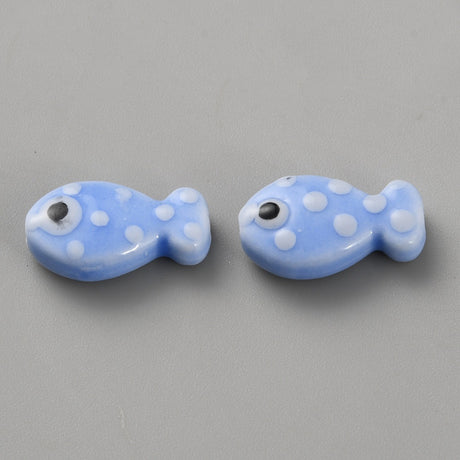Two blue fish-shaped beads with white polka dots on a gray background