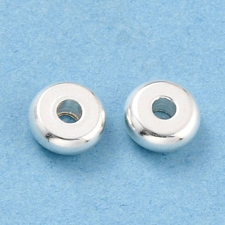 Two silver beads on a light blue background