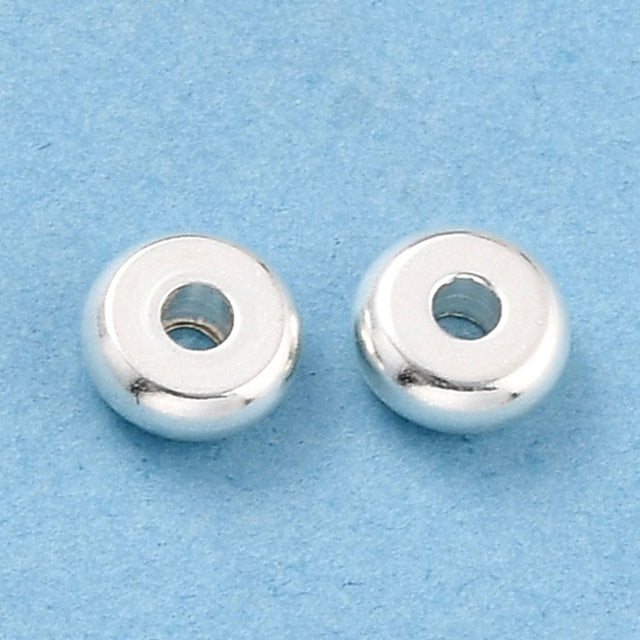 Two silver beads on a light blue background