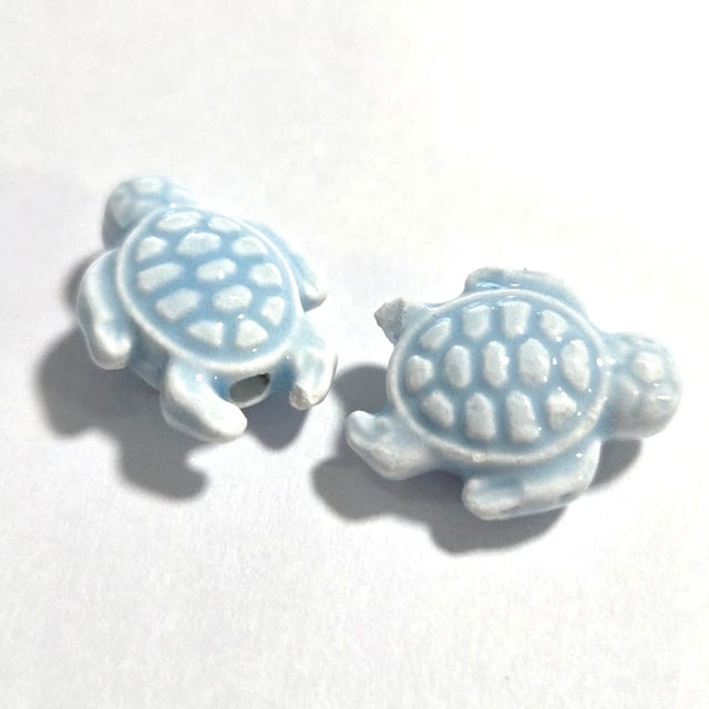 Two ceramic turtle beads on a white background