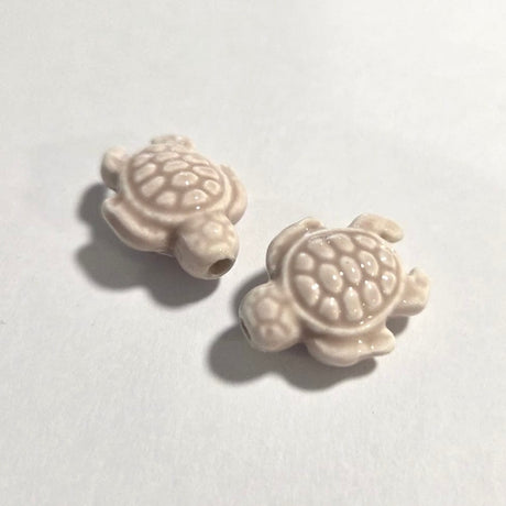 Two turtle-shaped ceramic beads on a white background