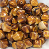 Close-up of amber-colored beads with brown and beige stripes on a white background