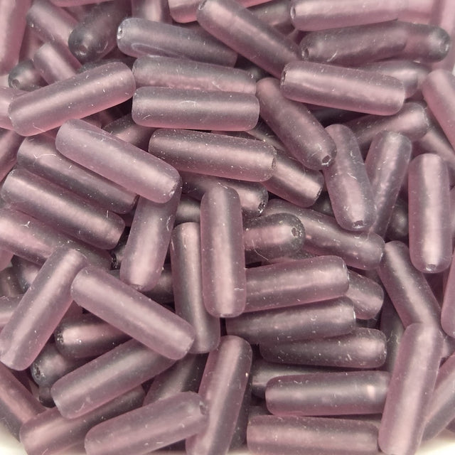 Close-up of purple cylindrical beads with visible threading hole for making jewelry or craft.