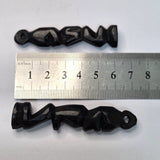 Two black wooden african folk art carvings on a white background with a ruler to show scale