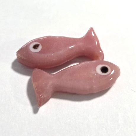 Two pink ceramic fish-shaped beads on a white background