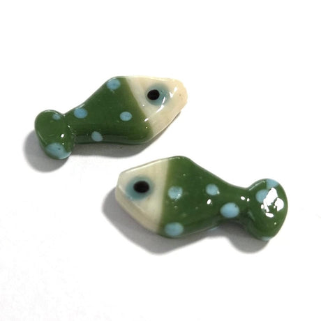 Two green ceramic fish-shaped beads with white polka dots on a white background