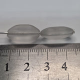 Close-up of white shield-shaped beads with a white background next to a ruler to show size