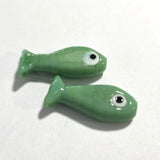 Two green ceramic fish-shaped objects on a white background