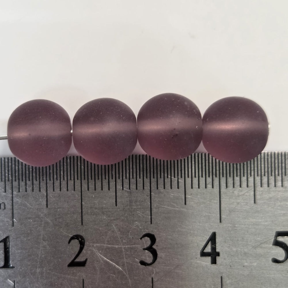 Three purple beads on a ruler for size reference