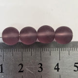 Three purple beads on a ruler for size reference