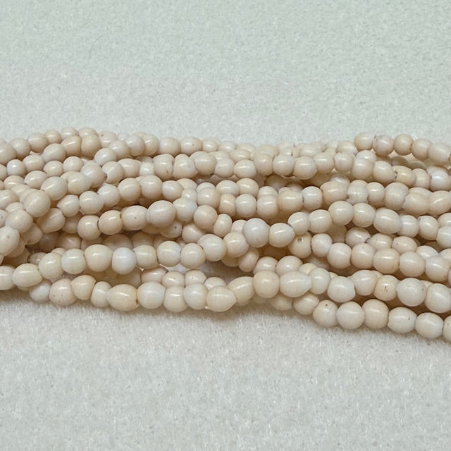 Strings of creaam round beads on a light gray background