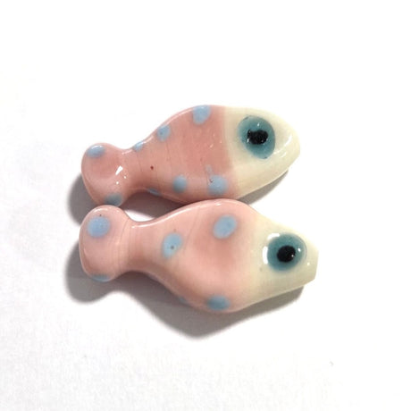 Two pink ceramic fish-shaped beads with blue spots on a white background