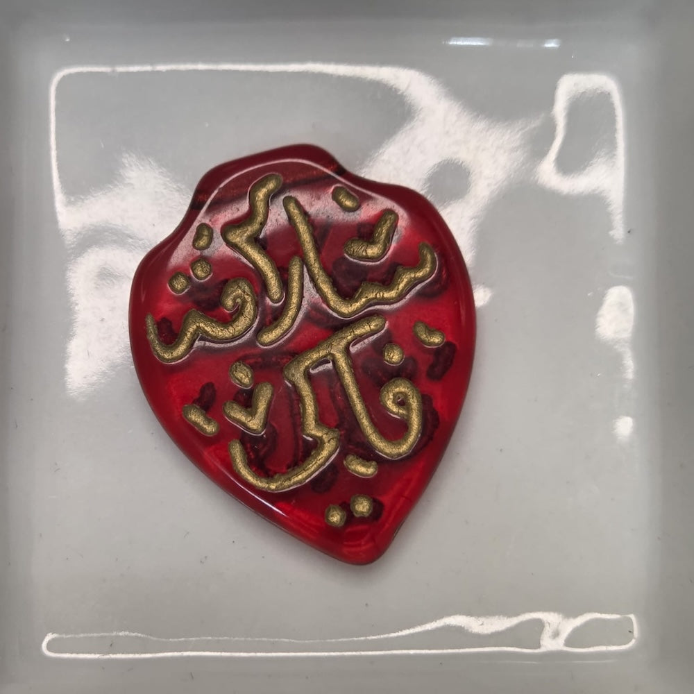 Red heart-shaped object with gold text on a white background