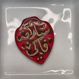 Red heart-shaped object with gold text on a white background