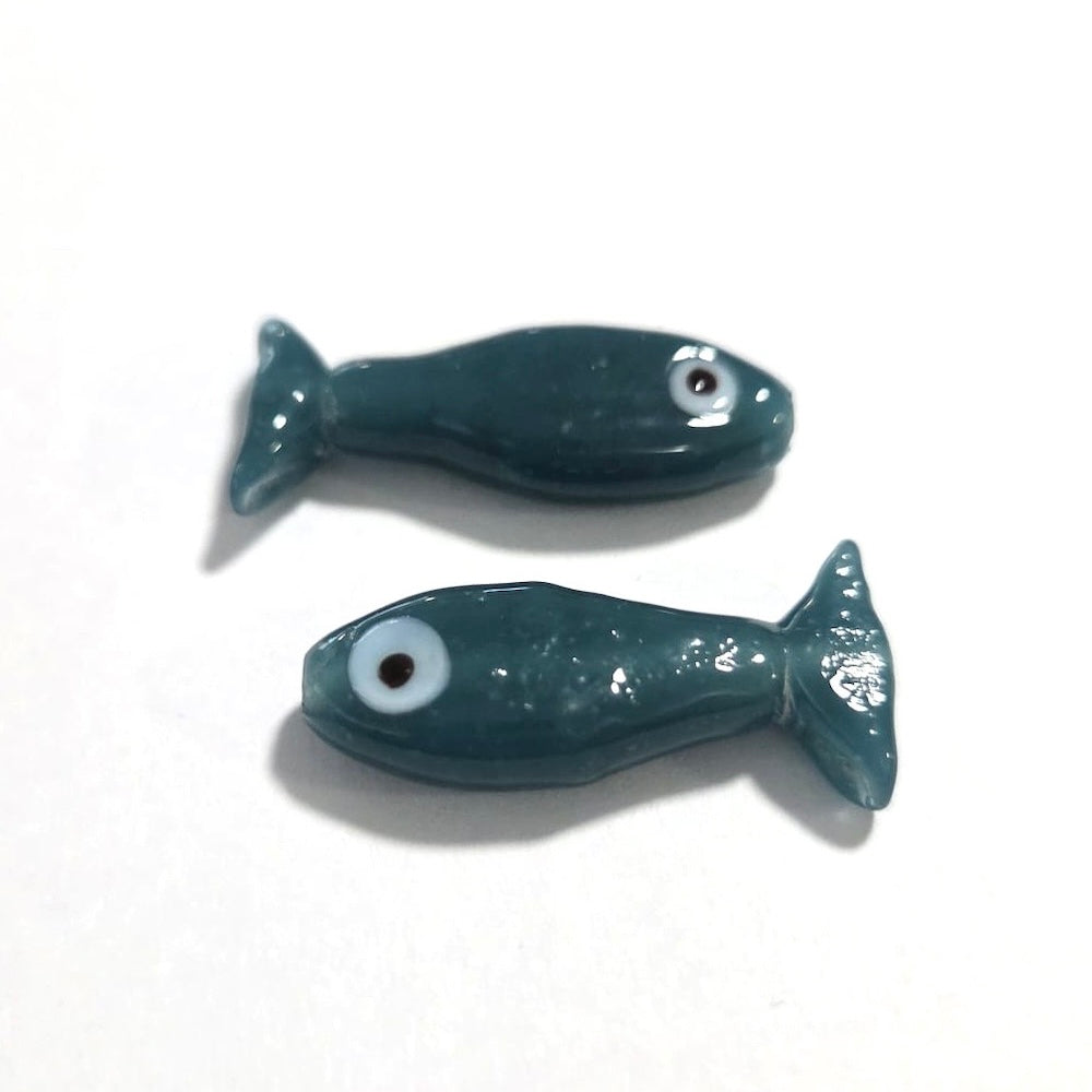 two sardine glass fish shape beads on a white surface