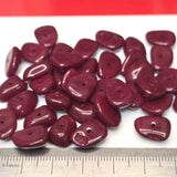 Maroon beads with a ruler for size reference on a white background