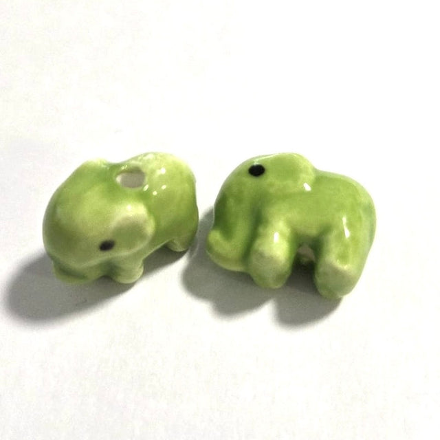Two small green ceramic elephants on a white background
