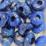 Blue donut  shape beads that look like rocks on a white background