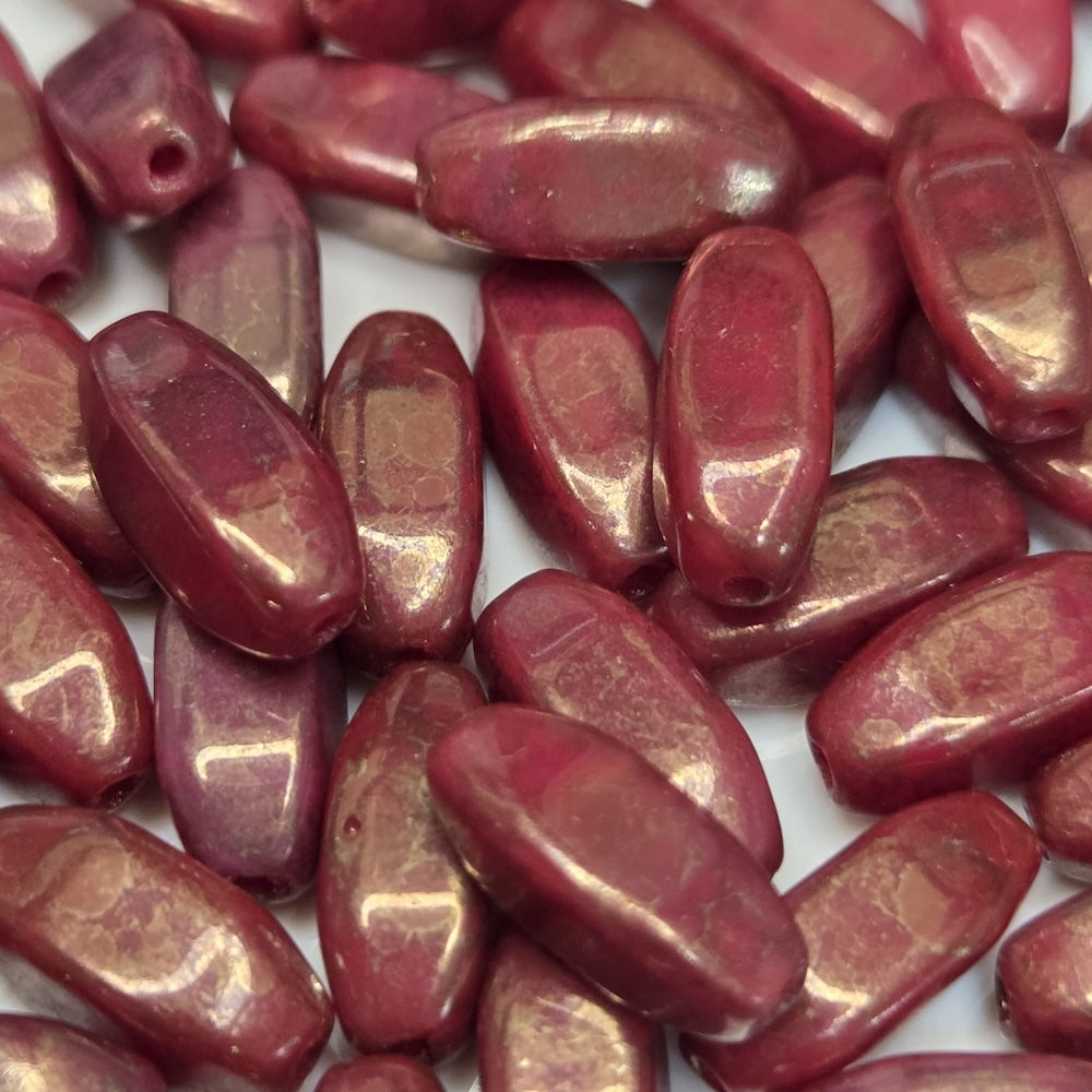 Close-up of red oval beads with a gold sheen on a white background