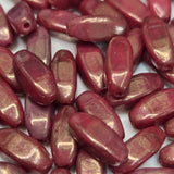 Close-up of red oval beads with a gold sheen on a white background