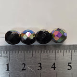 Four faceted beads with metallic iridescent finish on a ruler for scale.