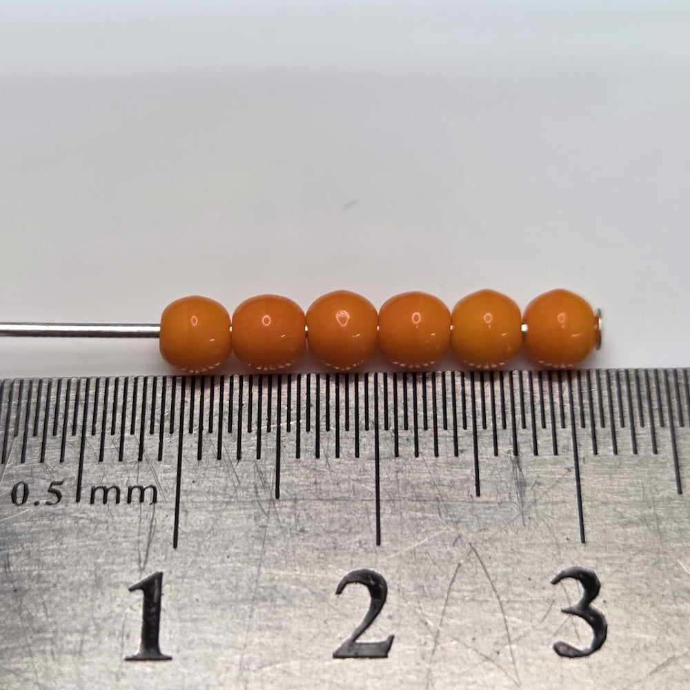 Orange beads on a ruler for size measurement
