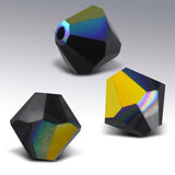 Three geometric crystal beads with multicolored facets on a gray background