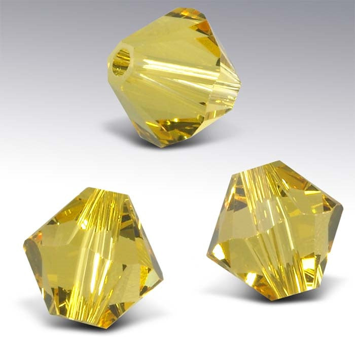 Three yellow crystal beads on a gray background