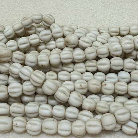 Close-up of shell color white beads on a textured surface