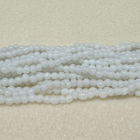 Strings of white opaque round beads on a light gray background