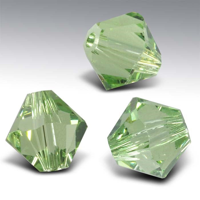 Three green faceted crystals on a gray background