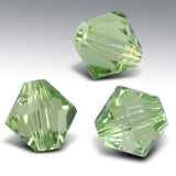 Three green faceted crystals on a gray background