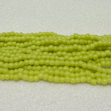 Strings of limey yellow round beads on a light gray background