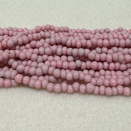 Strings of light dusty pink round beads on a light gray background