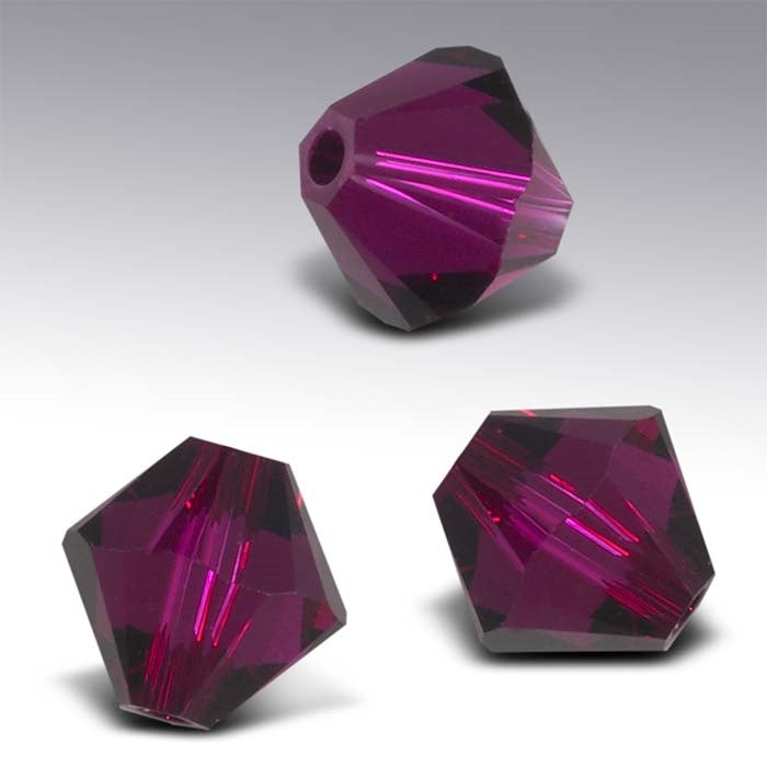 Three purple faceted beads on a gray background