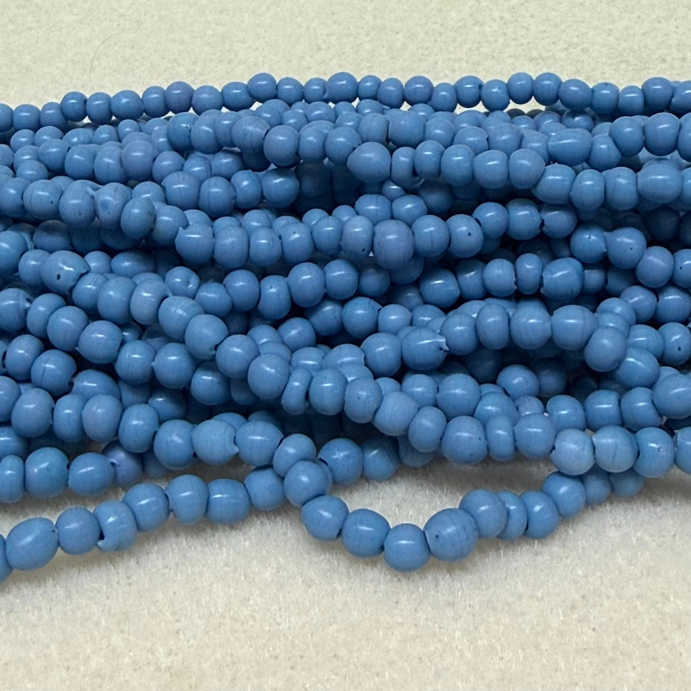 Strings of blue round beads on a light gray background