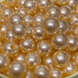 A collection of round vintage acrylic pearl beads in a cream color, stranded together.