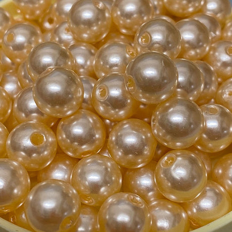 A collection of round vintage acrylic pearl beads in a cream color, stranded together.