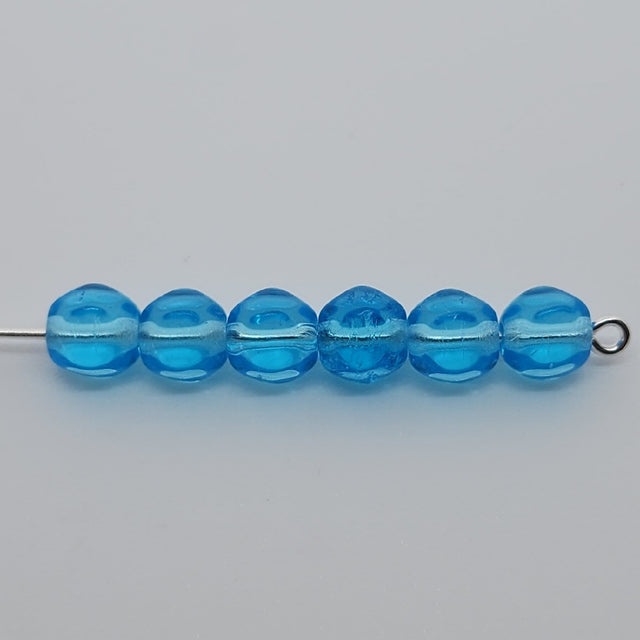 blue facet beads on a pin on a grey background