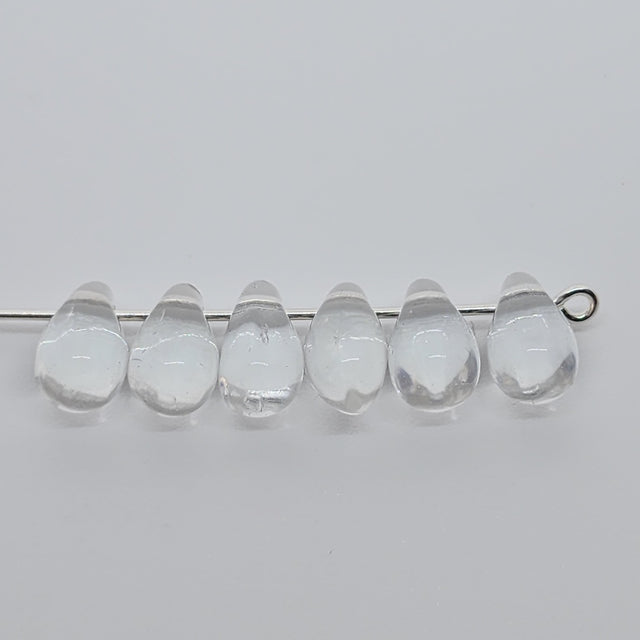 clear teardrop beads on a pin to show the threading hole on a grey background