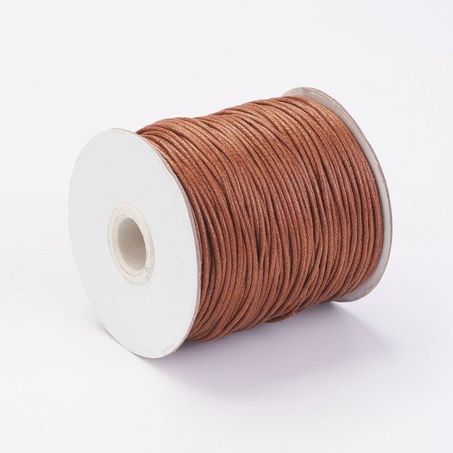 A spool of sienna brown wax cotton cord used for crafting and jewelry making.