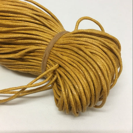 A bundle of yellow wax cotton cord, coiled and tied with a rubber band.