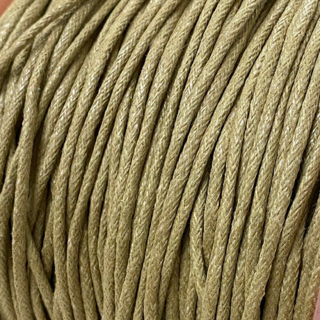 A spool of natural beige waxed cotton cord used for crafting and jewelry making.